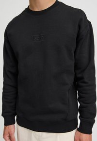 Schwarzes Sweatshirt aus Baumwollmischung, mit Rundhalsausschnitt, gerippten Bündchen und Saum, geprägtem Logo auf der Brust und lockerer Passform.
