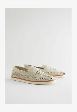 Loferi bej din material textil, cu un superior neted, talpă plată și împletituri decorative pe laturi. Design simplu, dar funcțional.