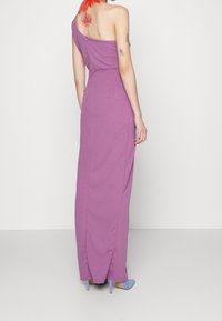 Violetti, yhdelle olalle suunniteltu maksimekko, jossa on vartalonmyötäinen yläosa, sivuaukko, takahaka ja sileä pinta. Mekossa on kukkatatuointi olkapään lähellä.