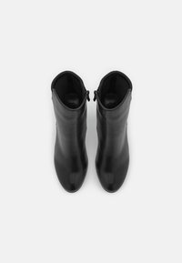 Botines de cuero negro con un diseño elegante, punta afilada y cierre de cremallera. Textura suave, estilo minimalista, sin patrones visibles.