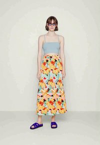 Top cropped azul claro, saia maxi floral em laranja, rosa e verde, e sandálias roxas. Tecido suave, top ajustado, design de saia solta.