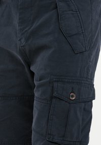 Pantaloni cargo navy realizzati in tessuto resistente, dotati di una tasca laterale con chiusura a bottone e dettagli di cucitura a vista.