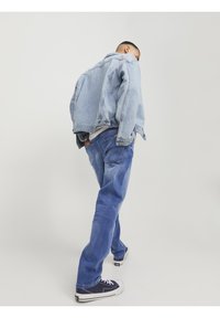 Ljusblå denimjacka med en avslappnad passform, parat med mörkblå jeans. Har fickor, knappstängning och en avslappnad design.