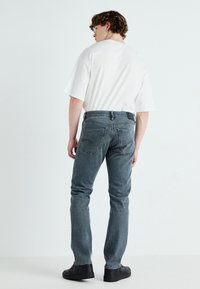 Jeans blu sbiaditi con un design classico, caratterizzati da gamba diritta, cinque tasche e una toppa in pelle nera sulla vita.