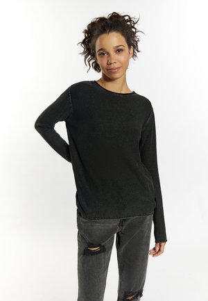 Schwarzer, gestrickter Pullover mit langen Ärmeln, texturiertem Muster und weitem Halsausschnitt, kombiniert mit zerstörten, dunkelgrauen Jeans.