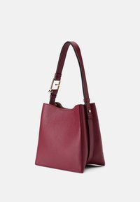 Bolso tipo bucket de cuero burdeos con superficie texturizada, una correa corta para el hombro, acentos de hardware dorado y diseño de parte superior abierta.