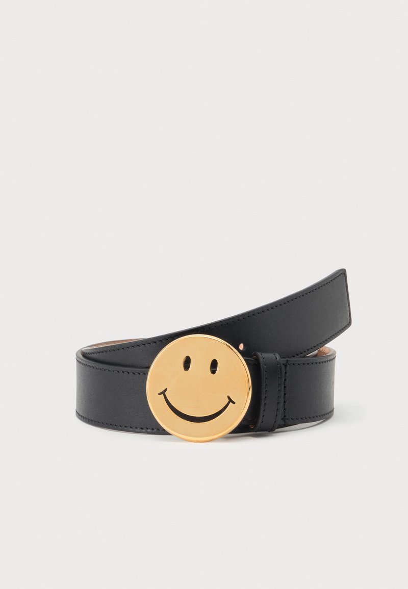Ceinture en cuir noir enroulée avec une grande boucle ronde en or ornée d'un motif de visage souriant noir.
