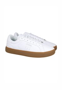 Zapatillas Joma blancas con parte superior de piel lisa, diseño con cordones, perforaciones para transpiración y suela de goma marrón.