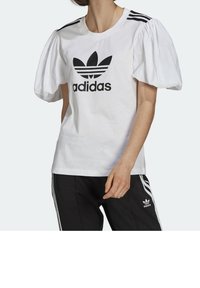 Camiseta blanca de manga corta con mangas abullonadas, que presenta un logo negro de Adidas y tres franjas negras en los hombros.