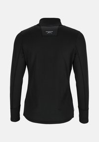 Musta pitkähiha shirt korkealla kauluksella, teksturoitu kangas ja logo selässä. Ominaisuuksiin kuuluu ommellut saumat ja istuva muoto.