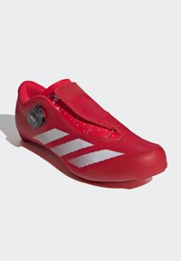 Czerwone buty rowerowe o gładkiej fakturze, systemie zapięcia BOA, górze z siateczki i trzema białymi paskami po bokach. Smukły design i aerodynamiczny kształt.