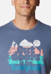 Camiseta de algodón azul con un diseño gráfico que presenta montañas, árboles y el texto "El aire libre es para todos" en colores contrastantes.