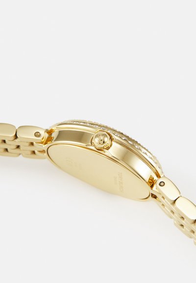 Gouden polshorloge zijaanzicht met kroon en schakelsarmband tegen een witte achtergrond zonder zichtbaar horloge.