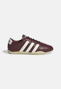 Baskets bordeaux profil bas avec des bandes Adidas blanches, semelle beige et lacets, vues de côté sur un fond gris clair.