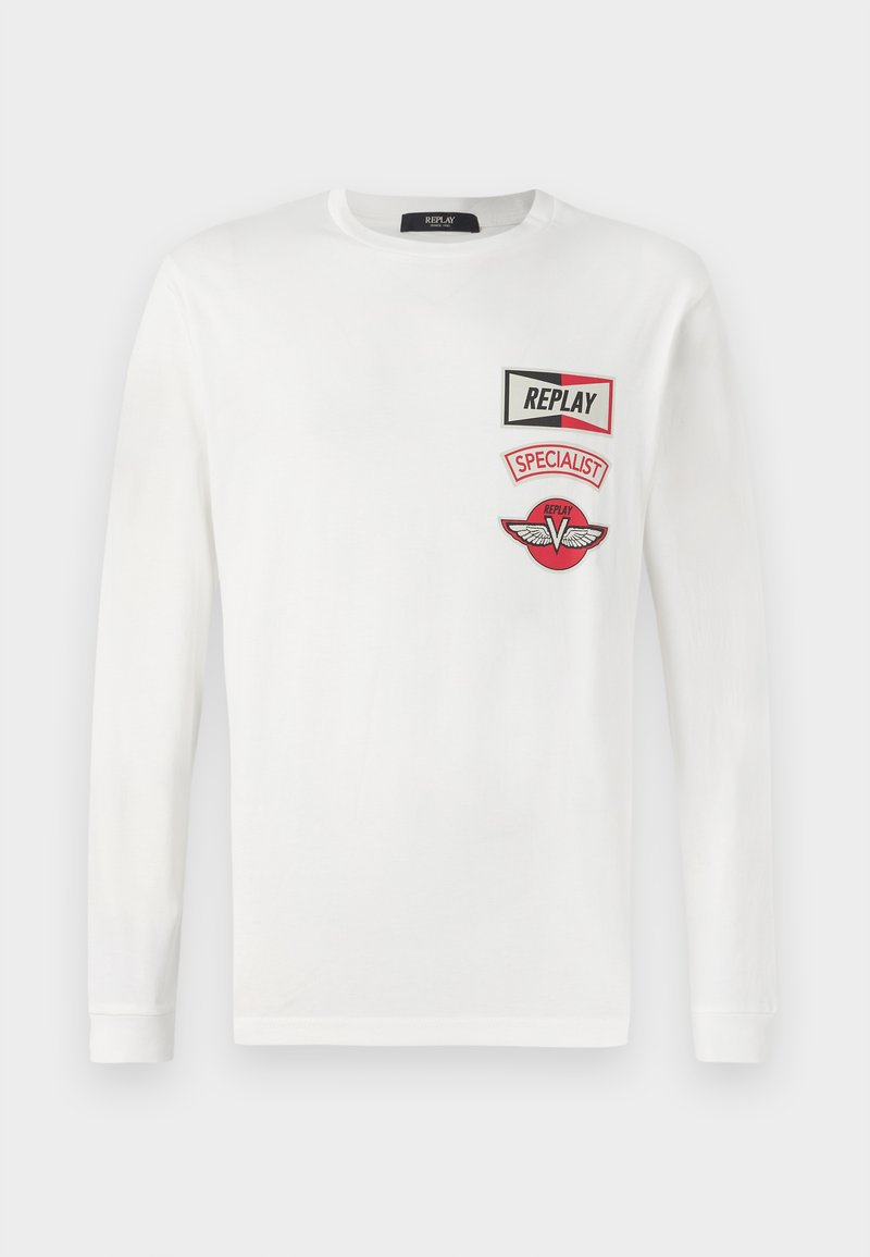 Witte langesleeve shirt met drie rode en zwarte patches op de linkerkant van de borst: "REPLAY," "SPECIALIST," en een vleugellogo van V.