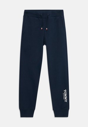 Tamsiai mėlynos spalvos sportinės kelnės, pagamintos iš medvilnės mišinio, su nusegamu juosmens dirželiu, šoninėmis kišenėmis ir 'Tommy Hilfiger' logotipu kairėje kojoje.