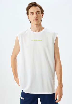Witte mouwloze sportshirt gemaakt van ademend materiaal, met een gele tekstontwerp dat in het midden "HOUD DOOR MET VOORUITGAAN" leest.