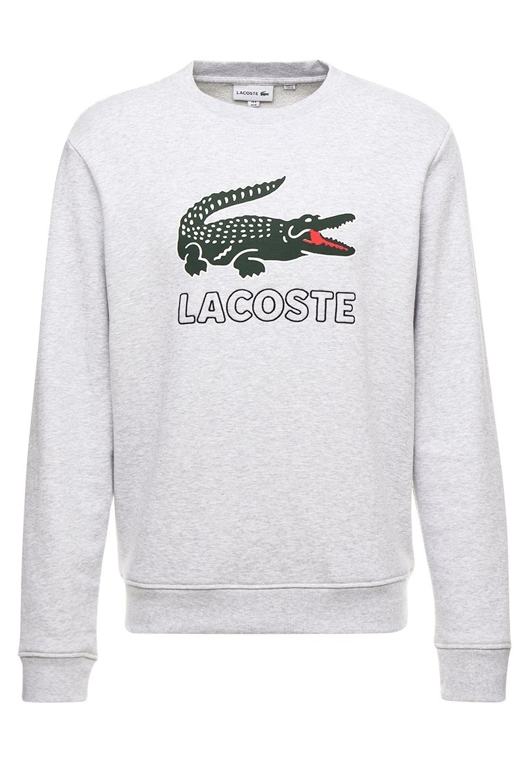 Grå sweatshirt med långa ärmar, med en grön krokodil-logotyp och ordet "LACOSTE" i fet svart text. Mjuk struktur, design med rundad hals.