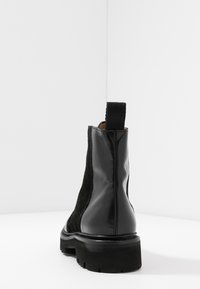 Czarne skórzane i zamszowe botki Chelsea z grubą podeszwą, elastycznymi bocznymi panelami oraz teksturowanym uchwytem z tyłu.
