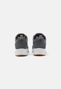 Gray athletic shoes with a textured finish, white soles, and gum rubber outsoles; features a tapered design and a small orange pull tab at the heel.