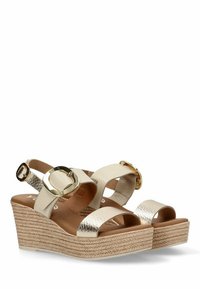 Sandalias de cuña con parte superior de imitación cuero en color beige, acentos metálicos y plantilla de yute trenzado. Diseño de punta abierta y correa ajustable en el tobillo.
