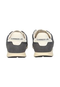 Coppia di sneaker nere e beige viste da dietro con la scritta "FLAMINGOS LIFE" sulla linguetta del tallone.