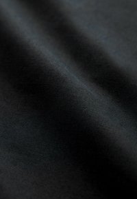 Țesătură neagră cu o textură netedă, având cute subtile și un model de țesătură uniform. Materialul pare moale și durabil.