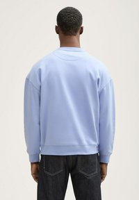 Lys blå sweatshirt med en afslappet pasform, ribbede manchetter og talje. Sweatshirten har en glat overflade og et enkelt design.
