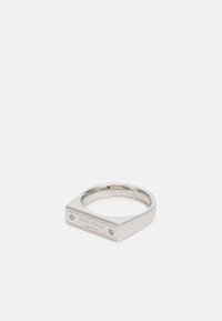 Inel din metal argintiu cu vârf pătrat, gravat cu "kate spade NEW YORK," având două pietricele mici transparente pe părțile laterale. Finisaj neted.