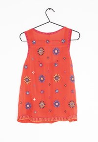 Top senza maniche rosso con ricami floreali in blu, giallo e rosa. Presenta un bordo di perline lungo il collo e l'orlo. Tessuto leggero.