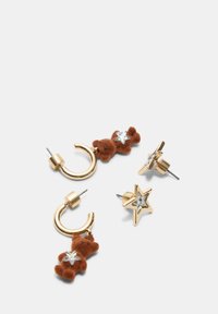 To sæt øreringe: det ene har guld hoops med en brun teddy bear charm og en stjerne, det andet har guld stjerner med klare sten.