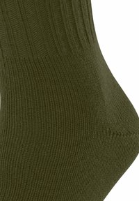 Olivgrüner Socke aus gerippter Strickware, mit einem dicken Bündchen und einer glatten Textur, die eine konturierte Form und eine nahtlose Zehenpartie betont.
