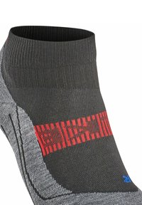 Schwarze Sportsocke mit niedrigem Schnitt, ausgestattet mit einem strukturierten grauen Panel und einem auffälligen roten Streifen an der Oberseite. Enthält blaue Akzentdetails.