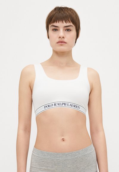 Biały top sportowy z szerokimi ramiączkami i niskim dekoltem. Posiada ciemno obrysowane logo "Polo Ralph Lauren" na elastycznym pasku.