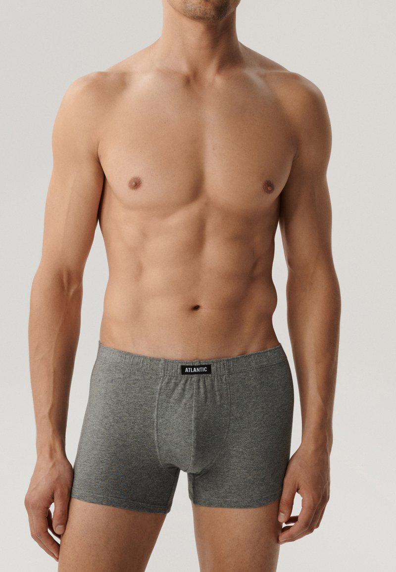 Szare bokserki o gładkiej fakturze, z miękkim pasem i metką z napisem "ATLANTIC" z przodu. Nosi je model męski.