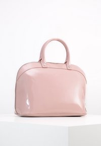 Różowa torebka z lakierowanej skóry o okrągłym kształcie, z podwójnymi uchwytami i zamknięciem na zamek. Gładka struktura i minimalne akcenty metalowe.