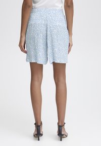 Ljusblå shorts med blommönster, gjorda av mjuk väv. Har en elastisk midja och en avslappnad passform som slutar ovanför knäet.