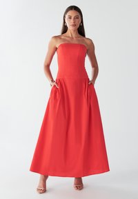 Punane rihmadeta maxi kleit, millel on kehasse vormitud bodi, voogav seelik, küljetaskud ja sile kangapind.