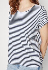Pruhované tričko s krátkým rukávem v krémové a námořnické modři, se zaobleným výstřihem a volným střihem, vyrobené z měkké, lehké tkaniny.