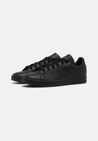 Sorte lædersneakers med en glat tekstur, rund tå og perforerede detaljer på siderne, med snørebåndslukning og flade gummisåler.
