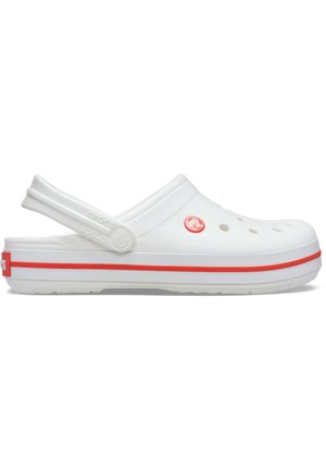 Białe klapki Crocs z otworami wentylacyjnymi, czerwoną paskiem na podeszwie, regulowanym pasek na piętę i czerwonym okrągłym logo po boku.
