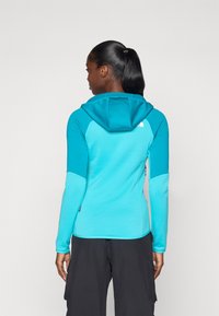 Felpa turchese con un design slim, caratterizzata da un colletto con zip e sezioni delle maniche a contrasto. Tessuto morbido con una texture liscia.