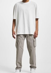 Wit katoenen T-shirt met korte mouwen, gecombineerd met lichtgrijze cargobroek met zijzakken, gedragen met witte sneakers.