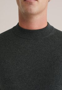 Sötét szürke kötött pulóver, bordás kerek nyakkal, lágy textúrával és sima felülettel, látható minták vagy díszítések nélkül.