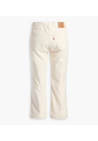 Jeans crème avec une coupe droite, dotés de poches arrière et d'une étiquette de logo brodée à la taille. La texture est lisse.