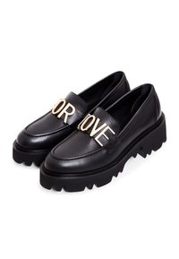 Mocassins en cuir noirs à semelle épaisse avec des lettres en métal doré formant le mot "FOR LOVE" sur les brides avant.