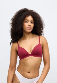Triangle σουτιέν σε σκούρο κόκκινο χρώμα, κατασκευασμένο από λείο ύφασμα με ρυθμιζόμενους ιμάντες. Διαθέτει αδιάφορο σχέδιο και μινιμαλιστικό στυλ.