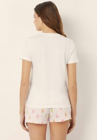 White short-sleeve cotton t-shirt paired with pink shorts featuring colorful ice cream and popsicle patterns. Smooth texture, relaxed fit.
