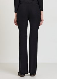 Schwarze, gerippte Strickhose mit auslaufendem Bein, hoher Taille und strukturiertem Finish. Ergänzt lässige oder halbformelle Kleidung.