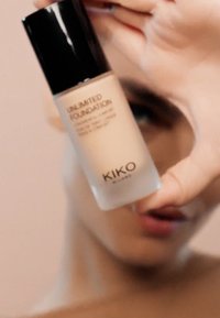 KIKO Unlimited Foundation i en klar glassflaske med svart lokk; har en lys beige væske og trykket tekst, som viser et minimalistisk design.